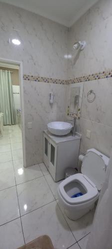La salle de bains blanche est pourvue de toilettes et d'un lavabo. dans l'établissement Macuco Departamentos, à Puerto Iguazú