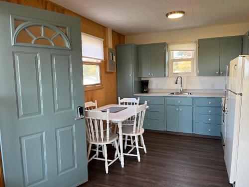 - une cuisine avec une table, des chaises et une porte dans l'établissement Little Haven Cottage an ocean view 2 bedroom cottage in Savage Harbour, à Mount Stewart