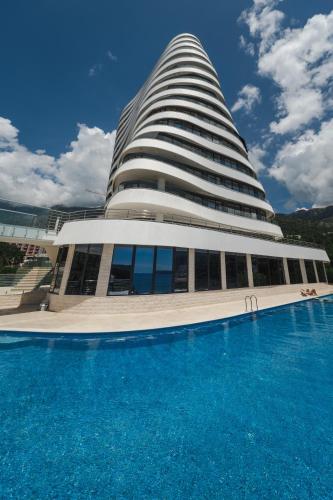 a building with a swimming pool in front of it at La barca apartments in Becici