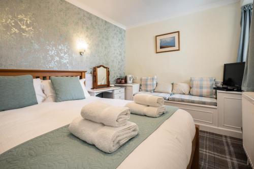 a hotel room with two beds and a couch at The Rowan Tree Country Hotel in Aviemore