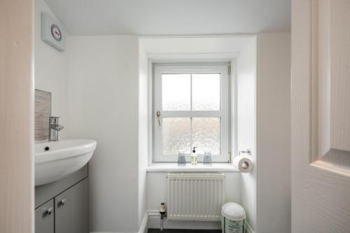 a white bathroom with a sink and a window at The Rowan Tree Country Hotel in Aviemore