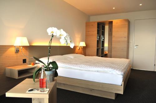 a bedroom with a bed and a table with a flower at Best Western Hotel Rebstock in Rorschacherberg