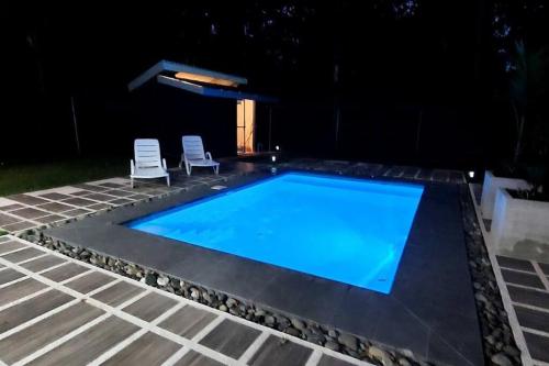 a swimming pool at night with two chairs and a swimming pool at CR Caribbean Blue House - Modern style 100 WiFi in Cahuita