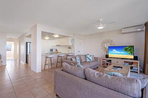 a living room with two couches and a flat screen tv at Beachfront Apt with rooftop spa across from Marcoola Beach in Marcoola