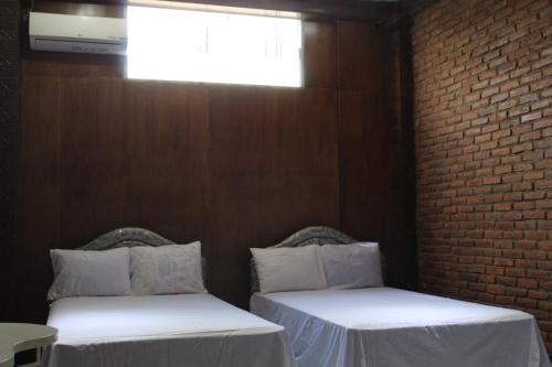 two beds in a room with a brick wall at Georium Dunia in Prambanan