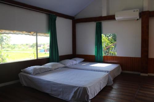 two beds in a room with two windows at Georium Dunia in Prambanan