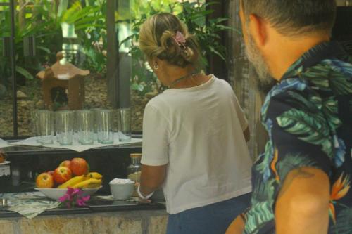 a woman standing next to a table with a tray of fruit at Pousada Aloha Beach House in Praia do Rosa