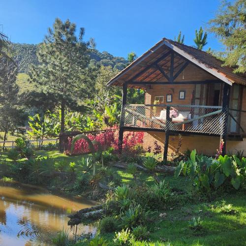 a house with a balcony next to a river at Pousada Vale Monte Azul in Santo Antônio do Pinhal