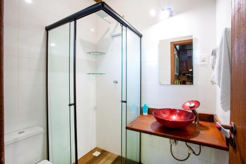 a bathroom with a glass shower and a red bowl on a counter at Casas Temporada Aldeia Niura Opy in Florianópolis