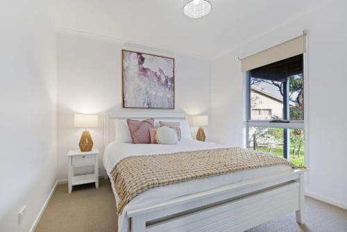 um quarto branco com uma cama e uma janela em Island Court em Smiths Beach