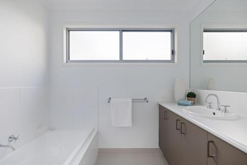 Baño blanco con bañera y lavamanos en Island Court, en Smiths Beach