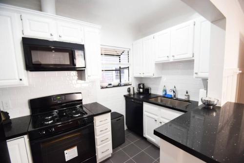 a kitchen with black appliances and white cabinets at Villa by the Ocean in Venice Beach in Los Angeles