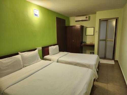 two beds in a room with green walls at U HOTEL in Skudai