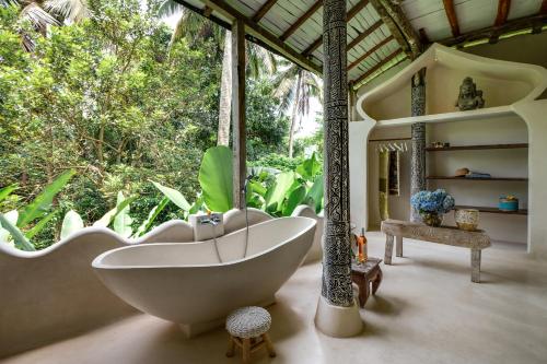 ein Bad mit einer Badewanne und einem großen Fenster in der Unterkunft The Rice Joglo Eco-Stay in Ubud