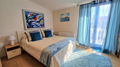 a bedroom with a bed with blue curtains and a window at Guest House Villa Ines - Annex in Zadar