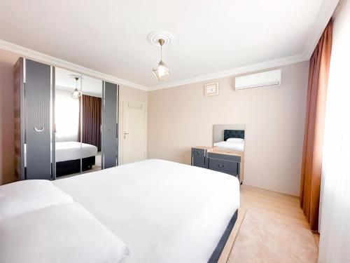 Grand Crown Suites - شقق غراند كراون السياحية في طرابزون: غرفة نوم بسرير ابيض ومرآة