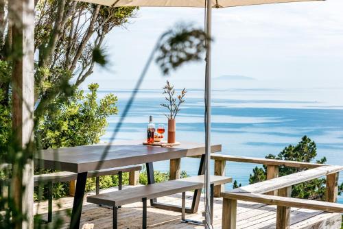 a table and benches on a deck with the ocean at The View - Coast & Country in Onetangi