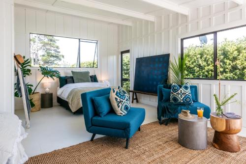 a bedroom with a bed and two blue chairs at The View - Coast & Country in Onetangi