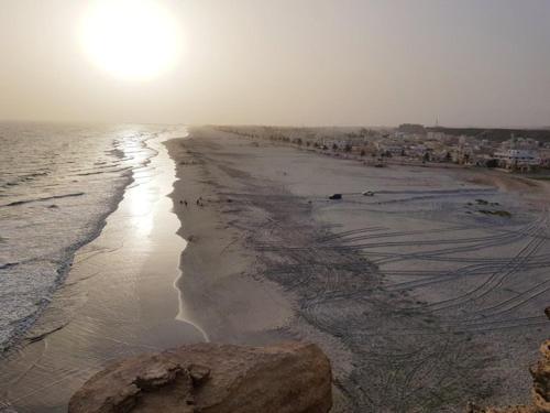 a beach with the sun shining on the water at نزل كوفان التراثي Koofan Heritage Lodge in Salalah