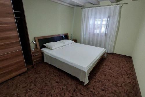 a bedroom with a white bed and a window at Apartments by the sea Cres - 21117 in Cres