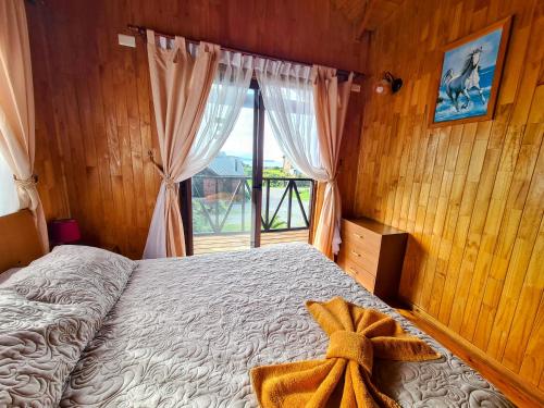a bedroom with a bed and a large window at Cabañas Kompatzki in Ancud