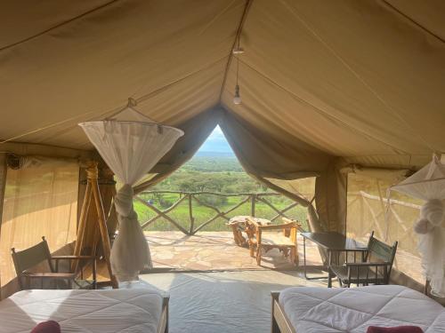 Zelt mit Betten und Stühlen und Aussicht in der Unterkunft Sunset camp in Narok