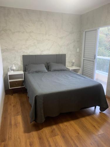 a bedroom with a large bed and a large window at Apto térreo novo 3 dorm - próximo ao centro in Poços de Caldas