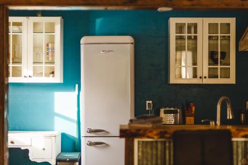 a kitchen with a white refrigerator and a blue wall at Tiny house & Sauna on Lakefront Farm Oasis in Merville