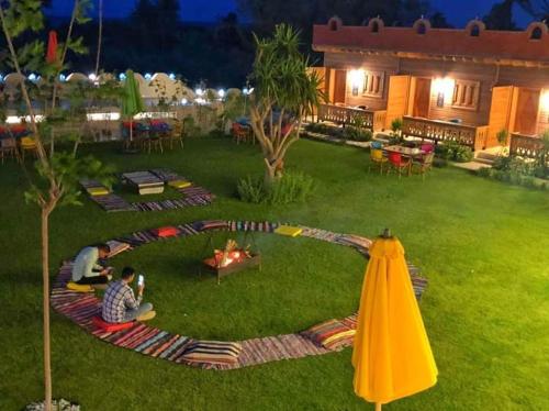 a group of people sitting in a yard with a fire in the grass at Tunis Pyramids Hotel - فندق اهرامات تونس in Tunis