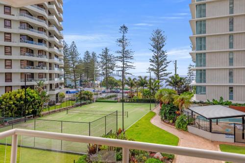 an apartment with a tennis court and two buildings at Burleigh Beach Tower in Gold Coast