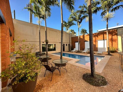 un patio con palmeras y una piscina en Oasis Tower Hotel en Ribeirão Preto