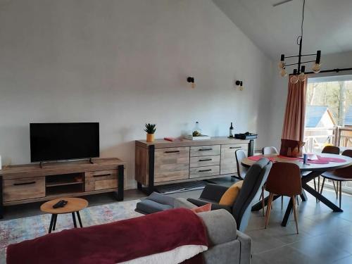 sala de estar con TV, mesa y sillas en Cosy chalet near Durbuy in nature, en Somme-Leuze