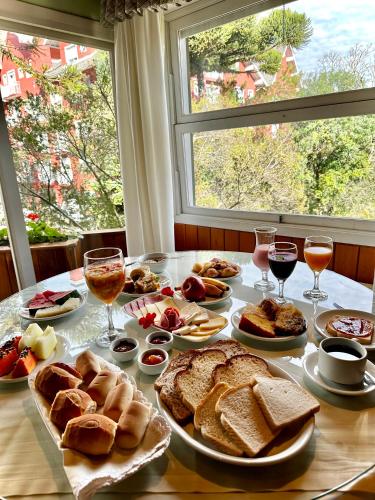 a table full of bread and wine glasses and a window at Natur Hotel - 700m da Rua Coberta in Gramado