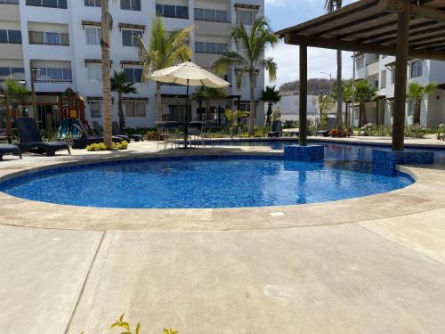 a swimming pool in a resort with an umbrella at Nuevo Departamento con Excelente Ubicación y Muy Bonita Alberca - Residencial Almarena II in Mazatlán