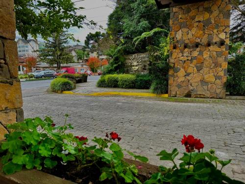 a courtyard with red flowers and a stone building at Natur Hotel - 700m da Rua Coberta in Gramado