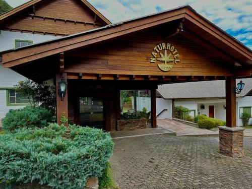 a building with a large entrance with a clock on it at Natur Hotel - 700m da Rua Coberta in Gramado