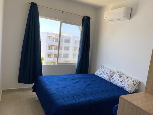 a bedroom with a blue bed and a window at Nuevo Departamento con Excelente Ubicación y Muy Bonita Alberca - Residencial Almarena II in Mazatlán
