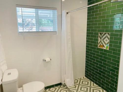 uma casa de banho com um WC e um chuveiro com azulejos verdes. em Modern + Midcentury House in B Bar H Ranch em Desert Hot Springs