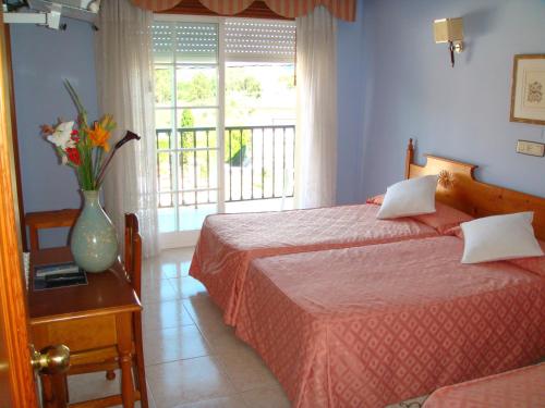 Hotel Vimar في سانكسينكسو: غرفة نوم بسريرين و مزهرية عليها ورد