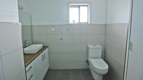 a white bathroom with a toilet and a sink at The Gull Ocean views family home Bermagui in Bermagui