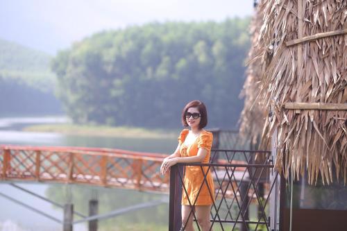 a woman in a yellow dress standing on a railing at KHU DU LỊCH SINH THÁI HÒN MÁT in Vĩnh Yên