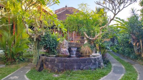 a garden with a fountain in front of a house at Uma Pejeng in Ubud