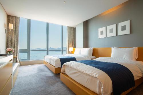 a hotel room with two beds and a large window at Sono Calm Yeosu in Yeosu