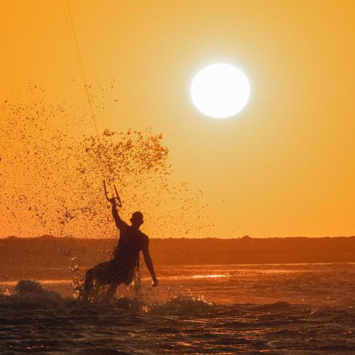 a man riding a horse in the water at sunset at Tatajuba Hostel Casa Pascual in Tatajuba