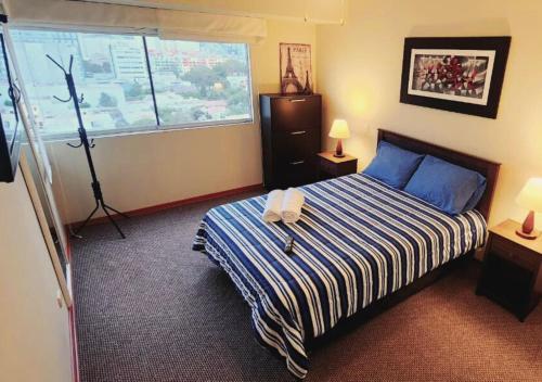 a bedroom with a bed with a blue and white striped blanket at Exclusivo Departamento 2BR en San Isidro in Lima