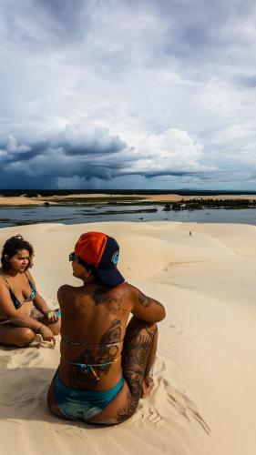 two people sitting in the sand on a beach at Tatajuba Hostel Casa Pascual in Tatajuba