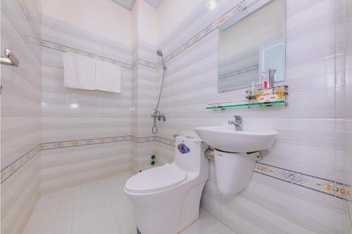 a white bathroom with a toilet and a sink at Magnolia Hotel Cam Ranh in Cam Ranh