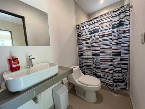 uma casa de banho com um lavatório, um WC e um espelho. em Tranquilidad y comodidad para ti em Cancún
