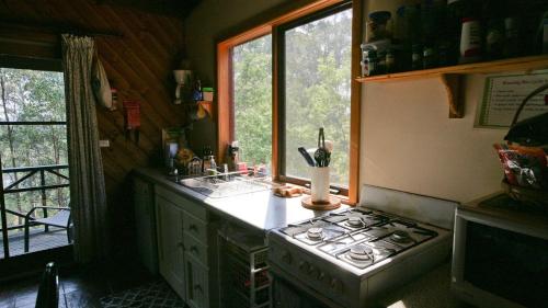 a small kitchen with a stove and a window at Nutley Cottage with river view Bermagui Linen provided in Bermagui