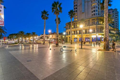 a city plaza with palm trees and buildings at night at Belle Escapes - Hidden Haven in Glenelg in Glenelg